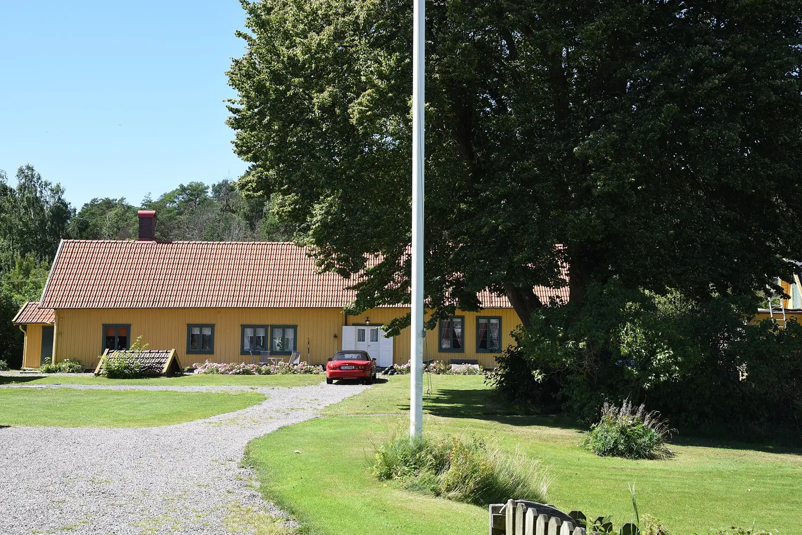 Gult gårdshus med tegeltak och stor lind på Onsalahalvön