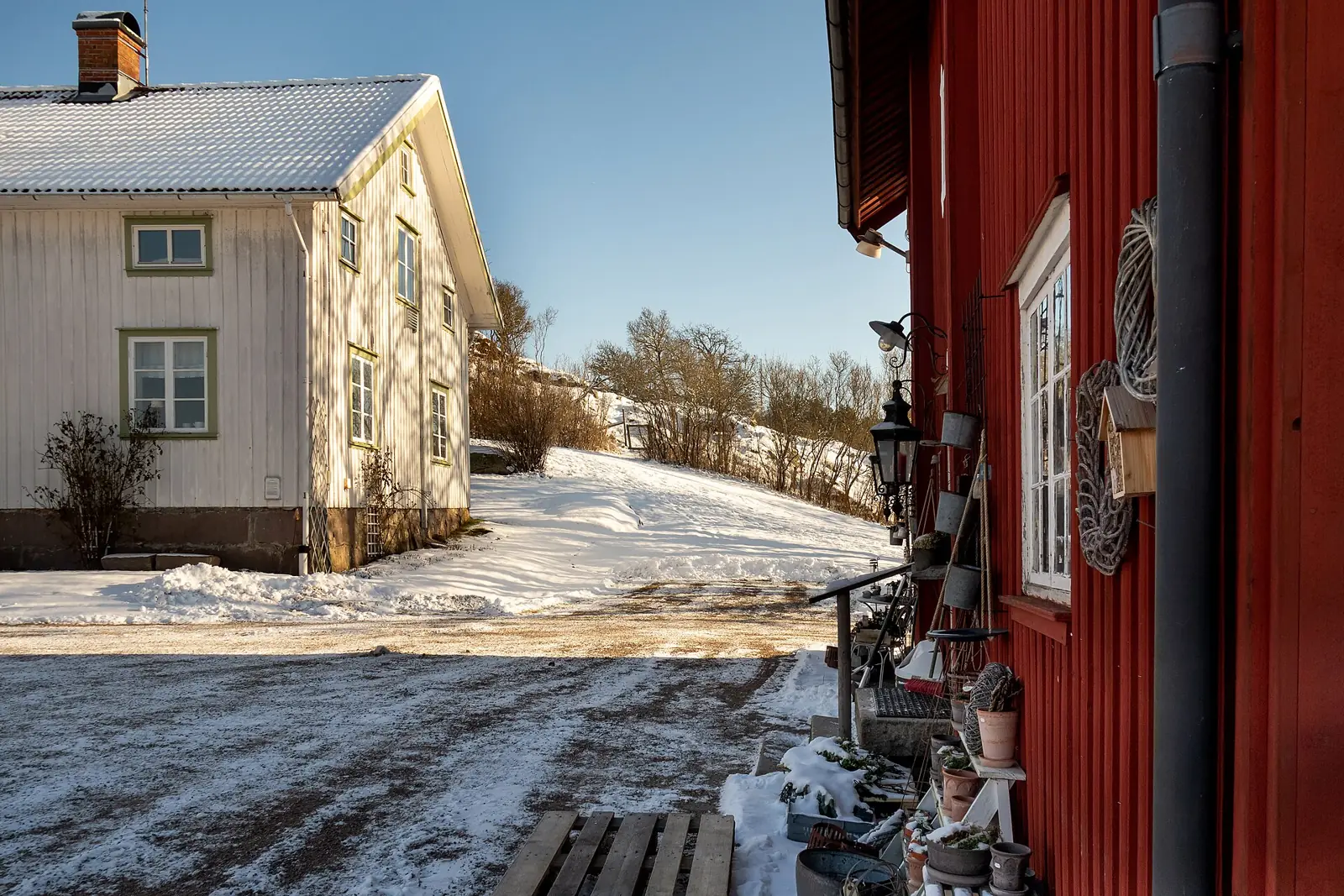 Vitt bostadshus och röd fasad med utomhuslykta en vinterdag