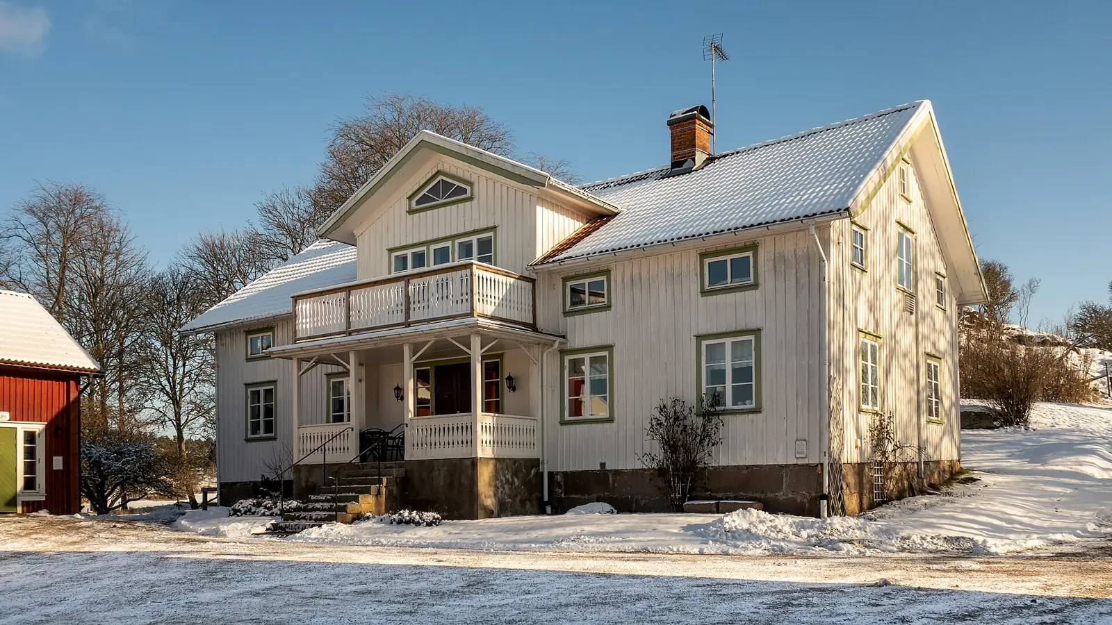 Vit sekelskiftesvilla med veranda i vintersol