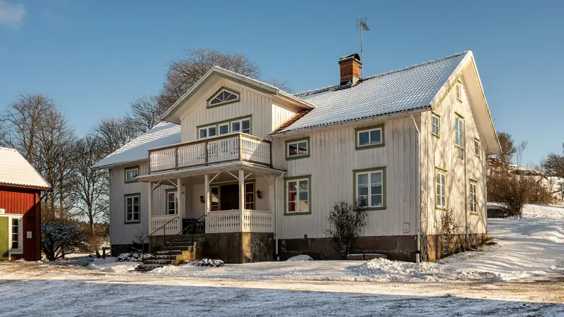Vit sekelskiftesvilla med veranda i vintersol