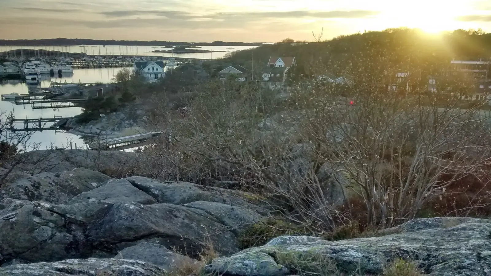Kvällsljus över hus och båthamn i Göteborgs skärgård
