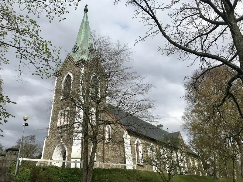 Västra Frölunda kyrka bland lövträd